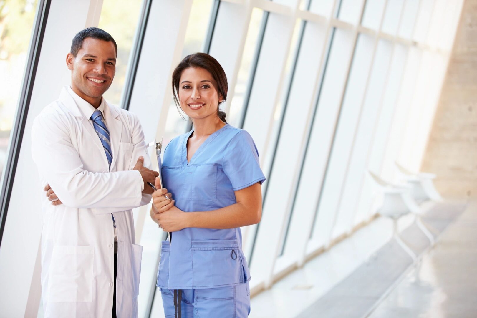 Doctor and nurse smiling in hospital hallway.